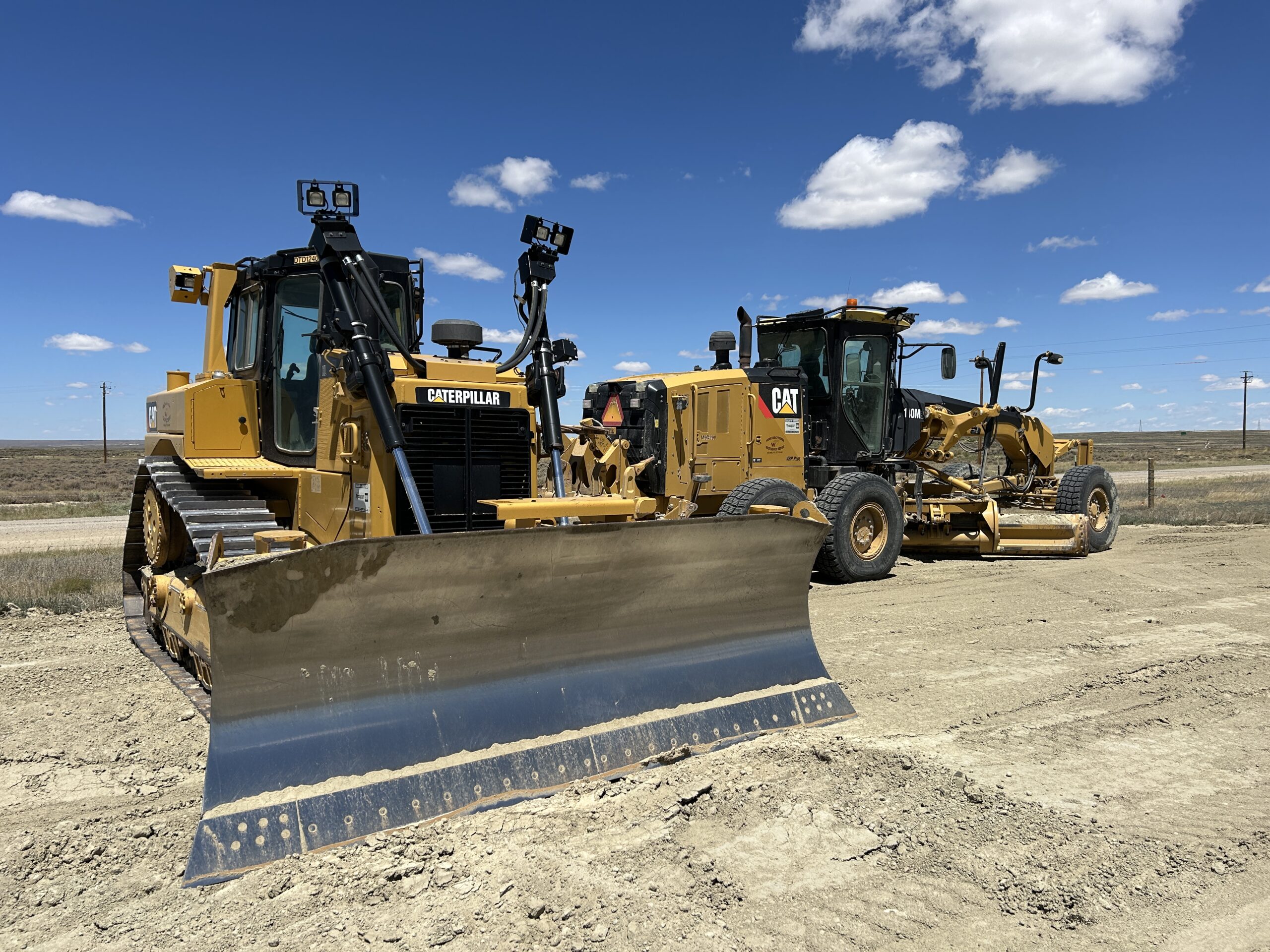 Two yellow bulldozers on dirt road.