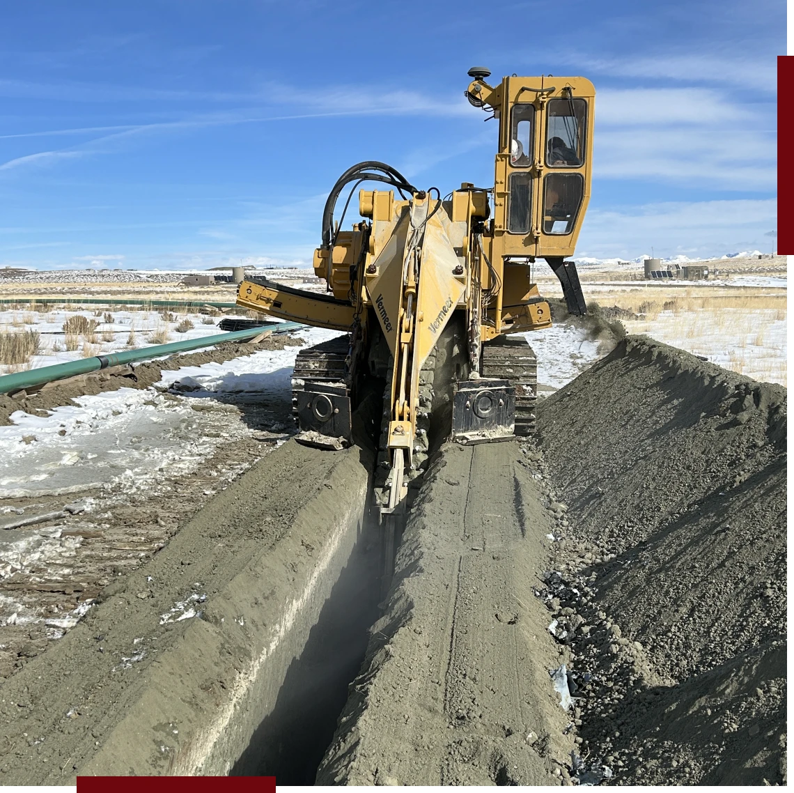 Machine digging trench in snowy landscape.