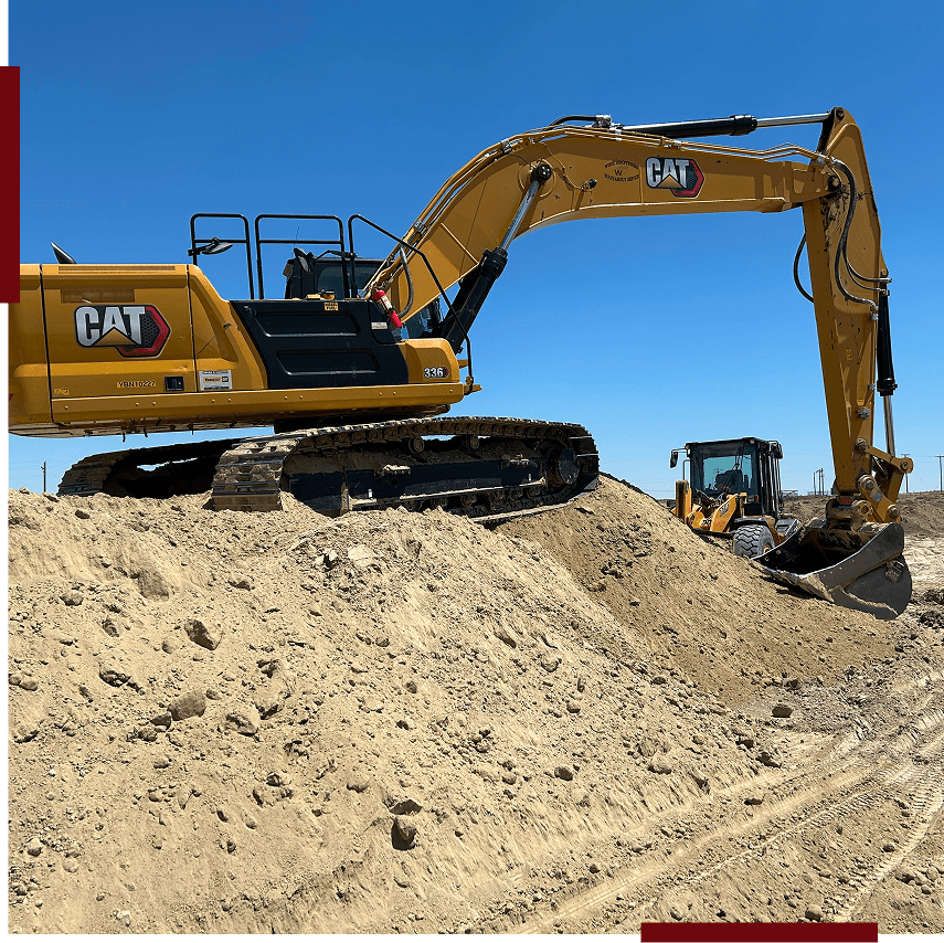 Excavator digging on a sandy construction site.
